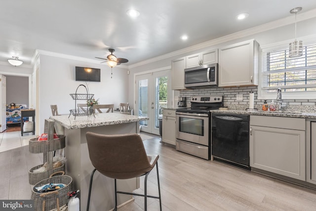 kitchen with a kitchen bar, light wood-type flooring, decorative backsplash, stainless steel appliances, and a sink