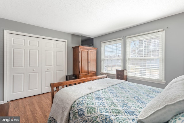 bedroom featuring a closet, a textured ceiling, and light wood-style flooring