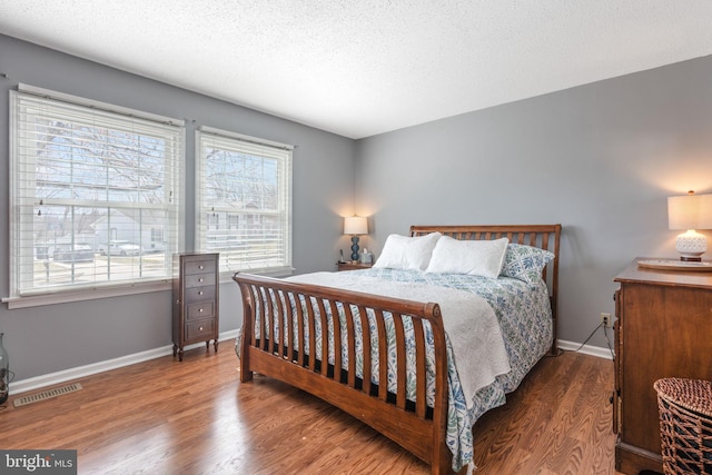 bedroom featuring multiple windows, wood finished floors, visible vents, and baseboards