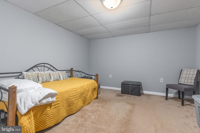 bedroom featuring a drop ceiling, light colored carpet, and baseboards