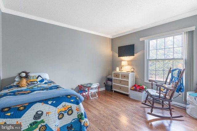 bedroom with a textured ceiling, wood finished floors, baseboards, and ornamental molding