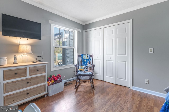 living area with baseboards, a textured ceiling, wood finished floors, and crown molding