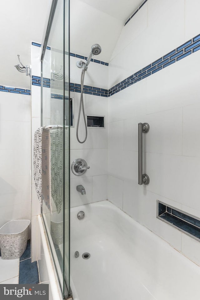 full bath with tile patterned flooring, tile walls, and combined bath / shower with glass door