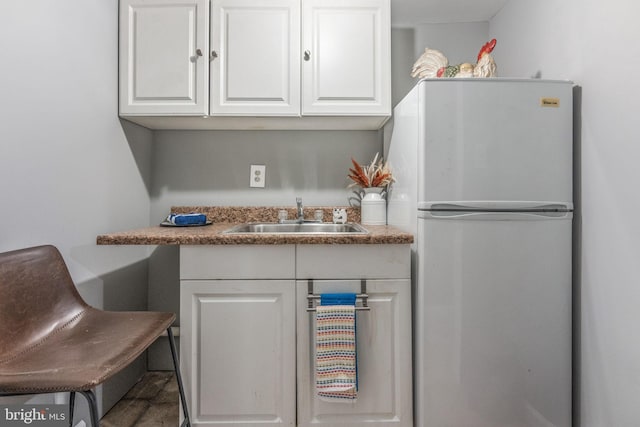 kitchen with a sink, white cabinetry, and freestanding refrigerator