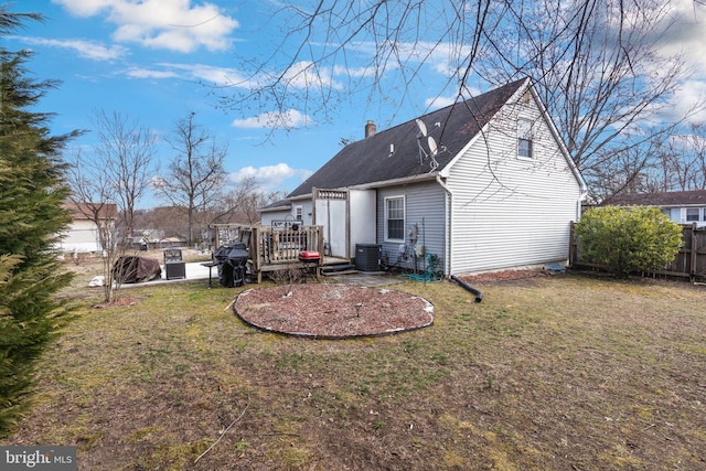 rear view of house featuring central air condition unit, a wooden deck, a yard, and fence