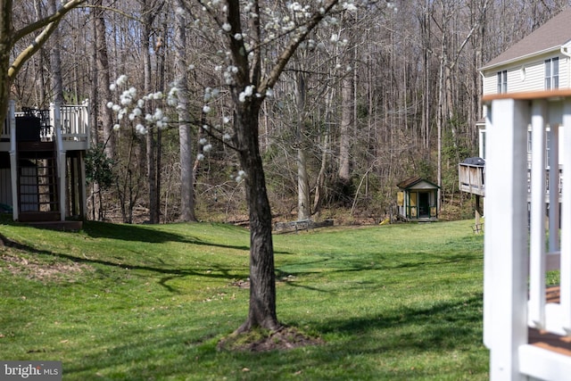 view of yard featuring a view of trees, a deck, and stairs