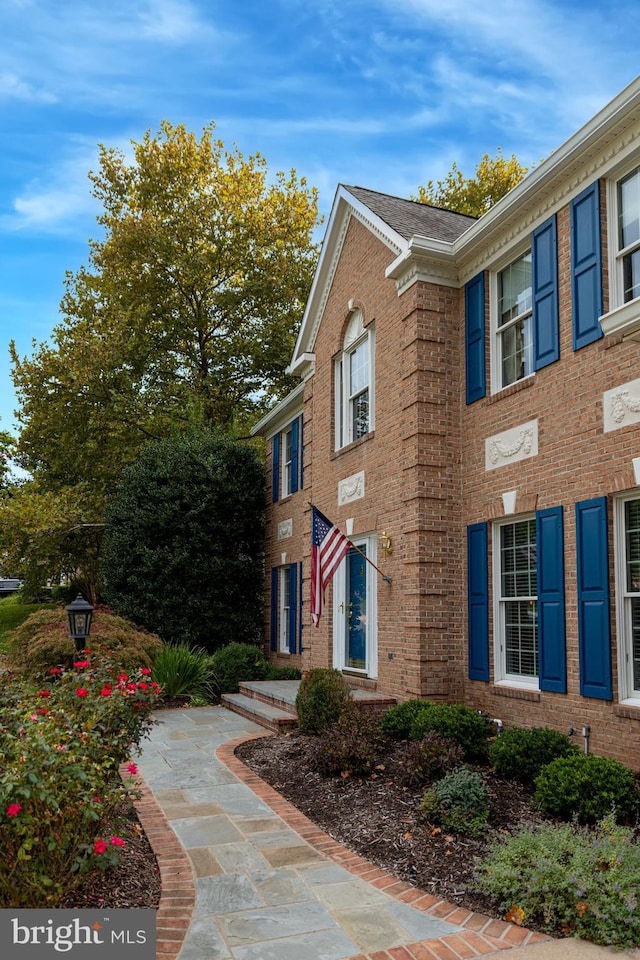 view of home's exterior featuring brick siding and a shingled roof