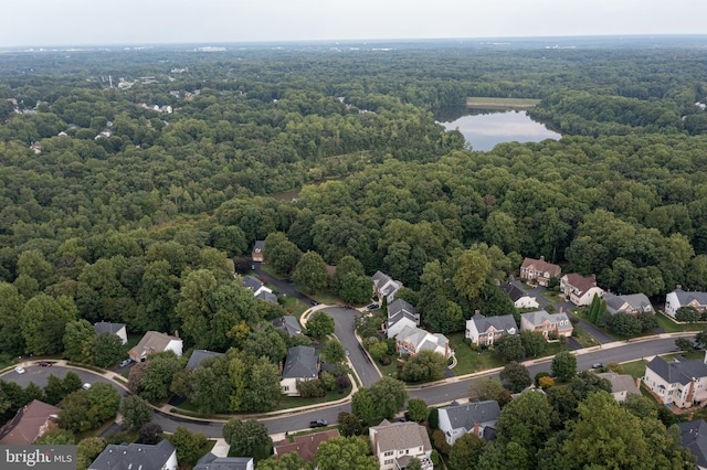 drone / aerial view featuring a residential view, a water view, and a view of trees