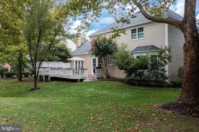 back of house with a lawn, a chimney, and a wooden deck