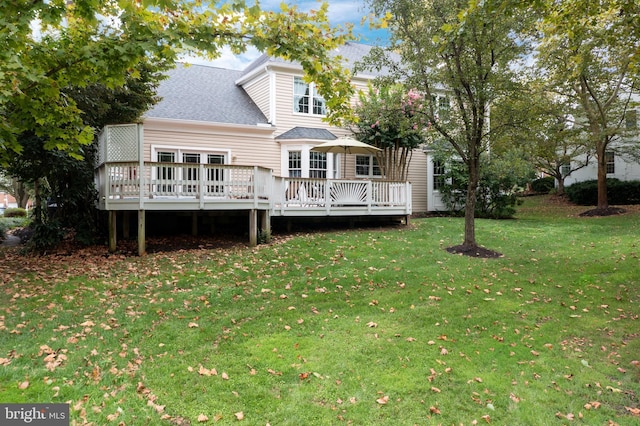 back of house featuring a lawn, roof with shingles, and a deck