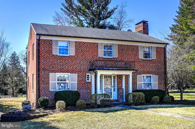 view of front of property with brick siding, a chimney, and a front yard