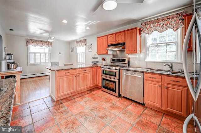 kitchen featuring stainless steel appliances, a baseboard heating unit, a ceiling fan, a sink, and under cabinet range hood