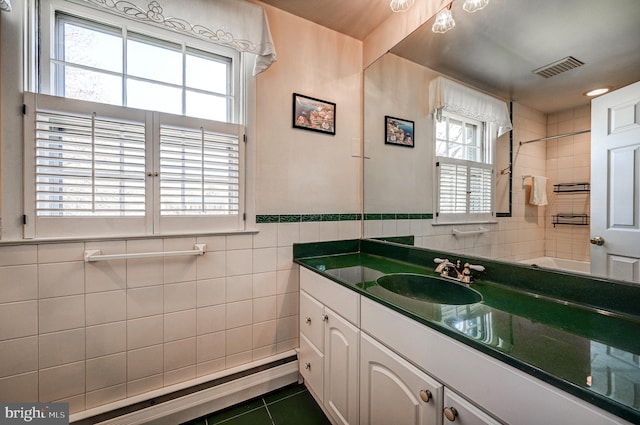 bathroom with vanity, a wealth of natural light, tile patterned flooring, and tile walls