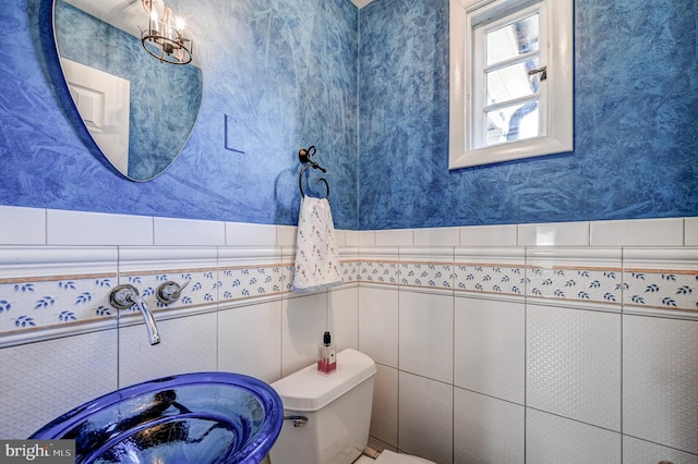 bathroom with wainscoting, toilet, and wallpapered walls