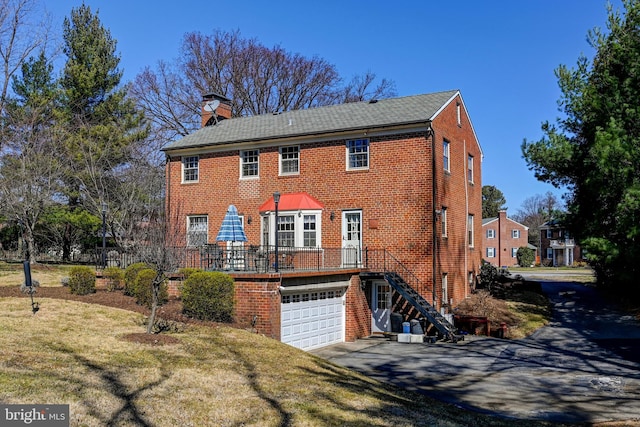 view of front facade with stairs, brick siding, a chimney, and aphalt driveway