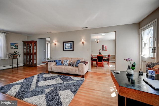 living room with a chandelier, visible vents, a baseboard heating unit, and light wood finished floors