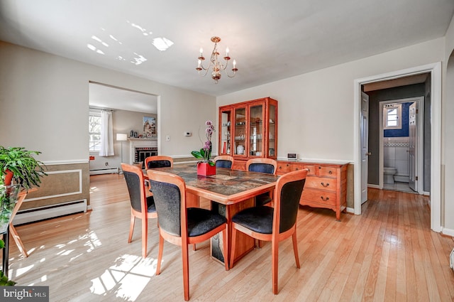 dining room featuring a baseboard radiator, an inviting chandelier, baseboard heating, light wood-type flooring, and a fireplace