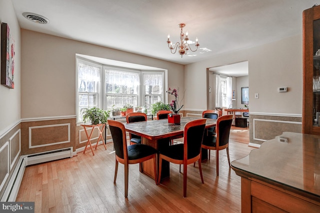 dining area featuring a wainscoted wall, light wood-style flooring, visible vents, and a notable chandelier