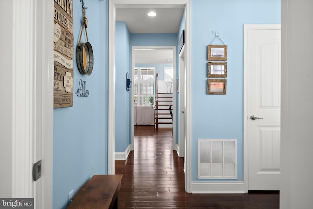 corridor with dark wood-style floors, stairway, visible vents, and baseboards