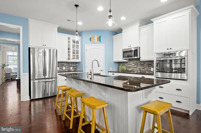 kitchen with appliances with stainless steel finishes, dark wood-style flooring, visible vents, and a sink