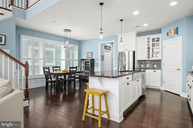 kitchen featuring stainless steel appliances, dark wood-type flooring, a sink, backsplash, and glass insert cabinets