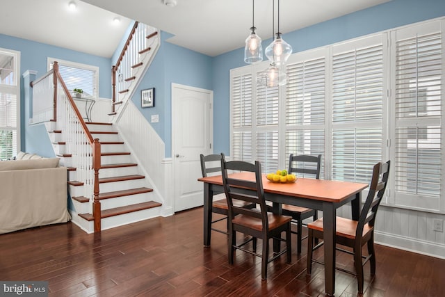 dining space featuring dark wood-type flooring and stairway