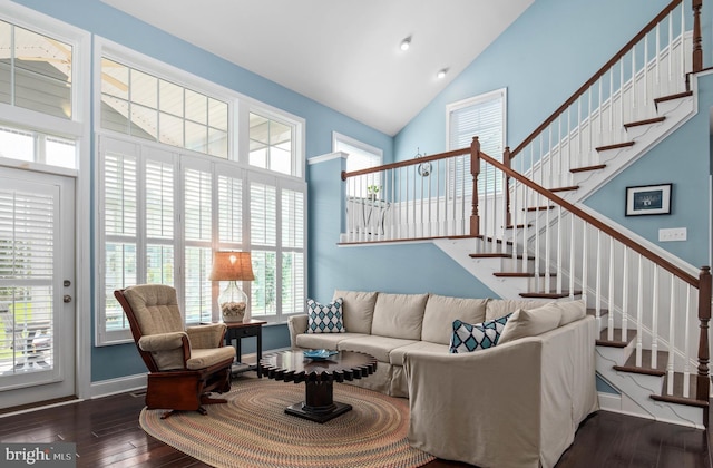 living area with stairway, wood-type flooring, high vaulted ceiling, and baseboards