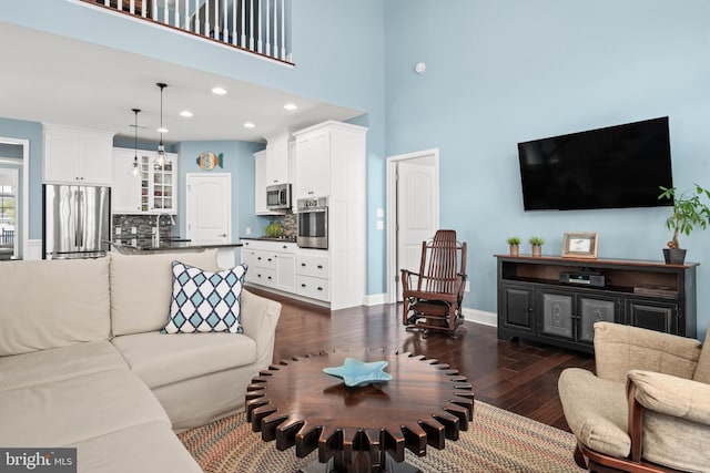 living room featuring dark wood-type flooring, recessed lighting, a high ceiling, and baseboards