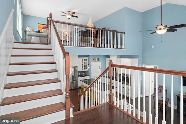 stairway with ceiling fan, high vaulted ceiling, and wood finished floors