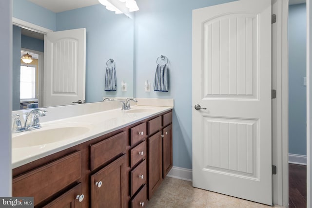 full bath with a ceiling fan, a sink, baseboards, and double vanity