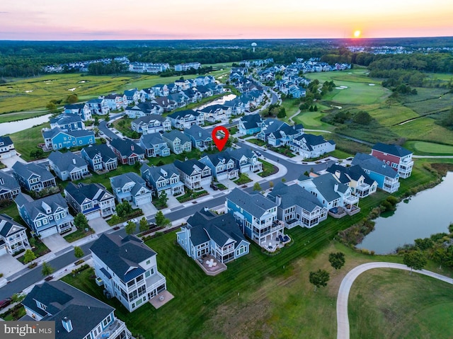 aerial view at dusk featuring a residential view and a water view