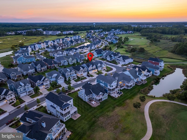 aerial view at dusk with a water view and a residential view