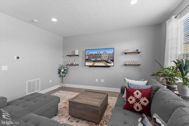 living room with recessed lighting, visible vents, baseboards, and wood finished floors