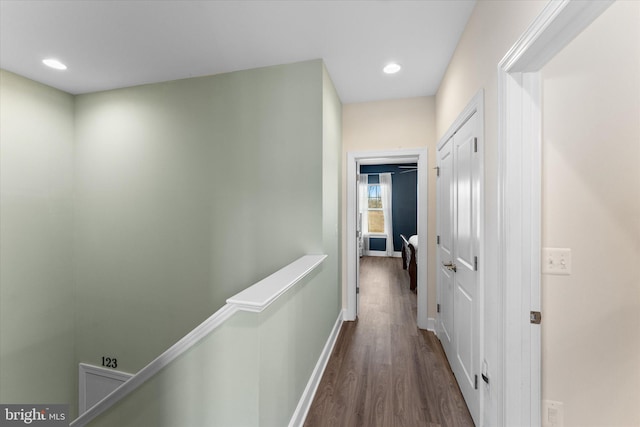 hall with recessed lighting, baseboards, an upstairs landing, and dark wood-style flooring