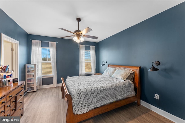 bedroom with ceiling fan, light wood-style floors, and baseboards