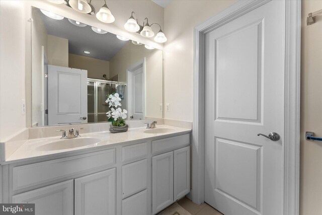 bathroom with a sink, a stall shower, and double vanity