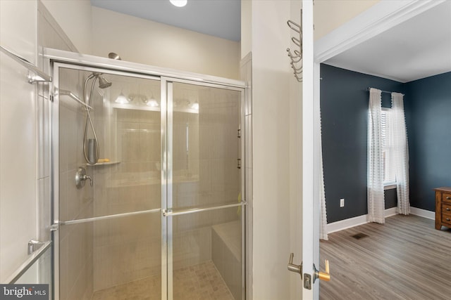 bathroom featuring visible vents, baseboards, wood finished floors, and a shower stall