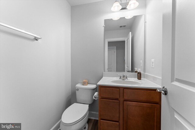 bathroom featuring visible vents, baseboards, toilet, and vanity