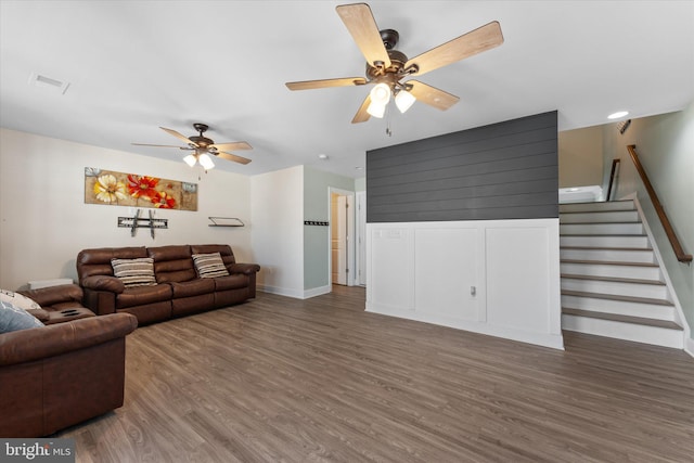 living room featuring visible vents, a ceiling fan, wood finished floors, stairway, and baseboards