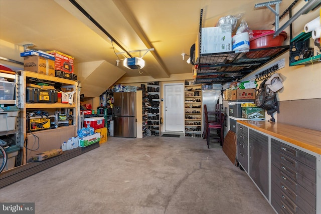 garage with a garage door opener and stainless steel refrigerator with ice dispenser