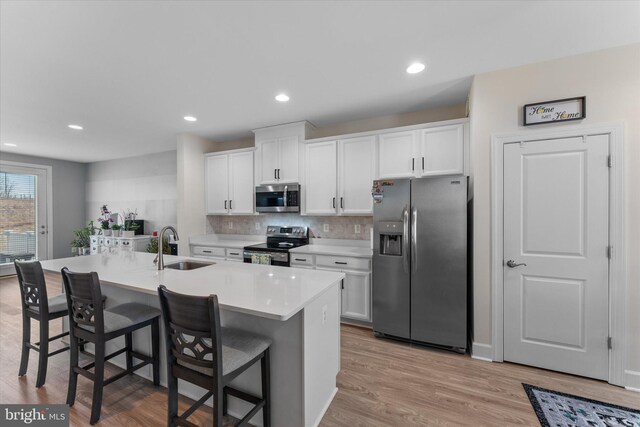 kitchen with white cabinets, appliances with stainless steel finishes, a kitchen bar, and a sink