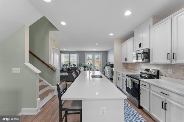 kitchen with open floor plan, white cabinets, appliances with stainless steel finishes, and a sink