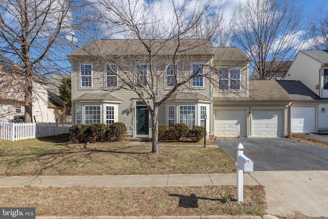 colonial house featuring an attached garage, a front lawn, fence, and aphalt driveway