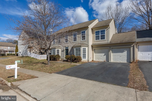 view of front of home featuring a garage, fence, and aphalt driveway