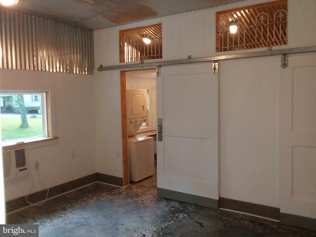 interior space with a closet, baseboards, unfinished concrete floors, and stacked washer / dryer