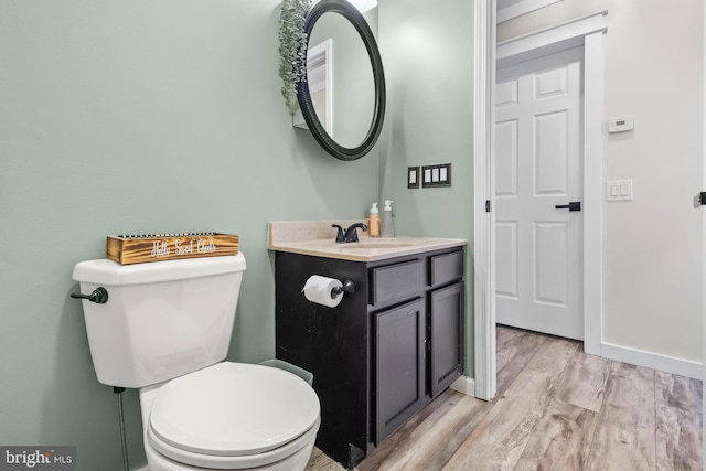 bathroom with vanity, wood finished floors, toilet, and baseboards