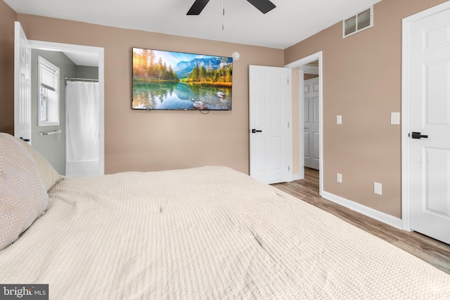 bedroom with a ceiling fan, visible vents, baseboards, and wood finished floors