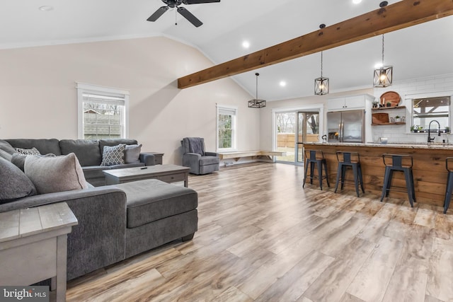 living room with vaulted ceiling with beams, ceiling fan, and light wood-style floors