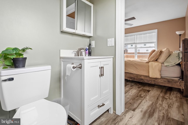 bathroom with toilet, ceiling fan, wood finished floors, and vanity