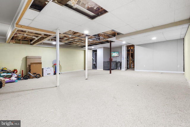 finished below grade area with a drop ceiling, concrete block wall, and baseboards